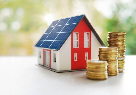 Energy efficient solar house House with solar panels and coin stacks.
